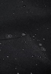 Water-resistant black fabric with a smooth texture, featuring droplets of water on the surface.