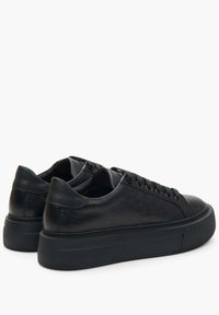 Black leather sneakers with a textured pattern, round toe, and flat rubber sole. Features laced closure and minimalistic design.