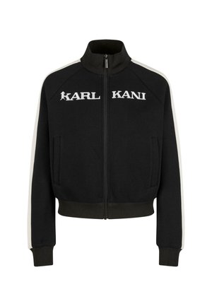 Black zip-up jacket with a high collar, featuring white side stripes and "KARL KANI" logo in bold letters on the chest. Smooth fabric texture.