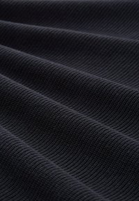 Texturiertes schwarzes Gewebe mit einem gerippten Muster, das weiche Falten zeigt. Das Material wirkt strapazierfähig und hat eine einheitliche, matte Oberfläche.