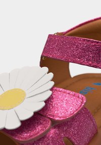 Ροζ παιδικό σανδάλι με γκλίτερ, διακοσμημένο με μια μεγάλη λευκή και κίτρινη μαργαρίτα στο λουράκι και καφέ εσωτερική σόλα.