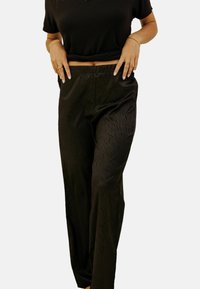 Pantalons en satin noir avec un design à jambes larges, présentant un motif texturé. La taille est élastique pour un maximum de confort, permettant une meilleure liberté de mouvement.
