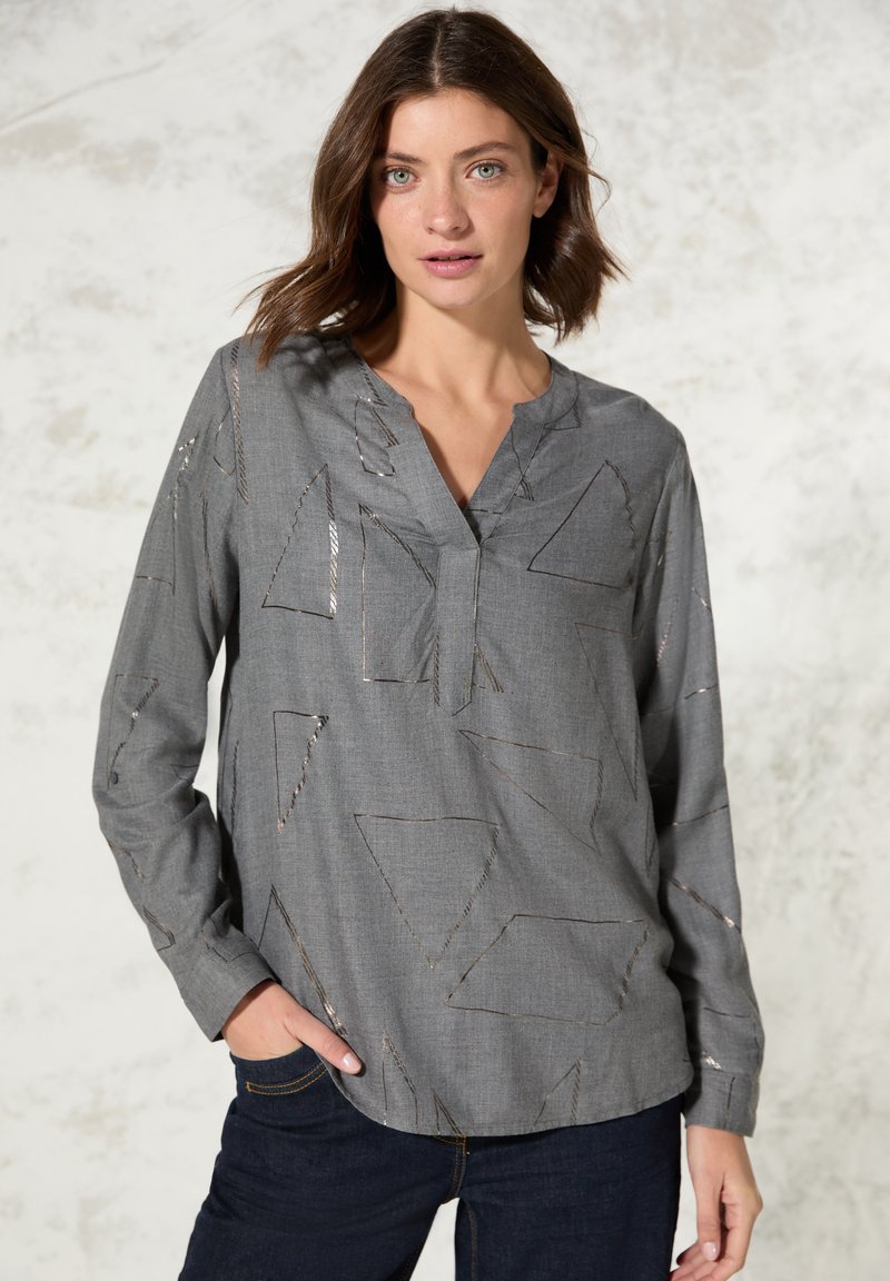 Graues Langarmshirt mit V-Ausschnitt und geometrischen Mustern in silbernem Garn. Hergestellt aus leichtem Stoff und mit einer lockeren Passform.