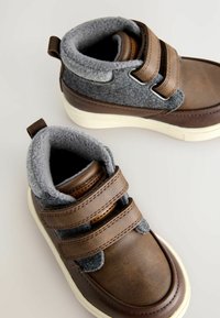 Czarne skórzane wysokie buty z szarymi tkaninowymi akcentami, z podwójnymi paskami na rzepy i białą gumową podeszwą. Miękka wewnętrzna wyściółka.
