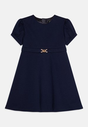 Vestido de manga corta azul marino con un cuerpo ajustado y falda acampanada, que presenta un detalle decorativo en dorado en la cintura y una textura suave.