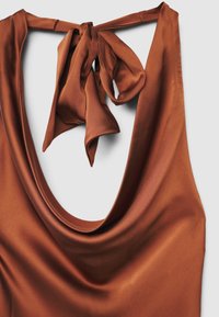 Haut en satin marron avec un décolleté profond en forme de U, doté d'un détail attaché au dos. Texture lisse, drapé fluide et éclat subtil sont les caractéristiques principales.