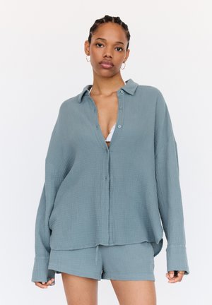 Light blue, textured button-up shirt with a collar, long sleeves, and a relaxed fit, paired with matching shorts in the same fabric.