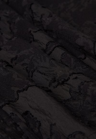 Black textured fabric featuring a subtle pattern, with layered folds creating depth. The material appears soft and slightly crinkled.
