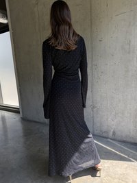 Robe noire à manches longues avec un corsage ajusté, une jupe fluide et des pois blancs. Fabriquée en tissu doux, elle présente un design enroulé à la taille.