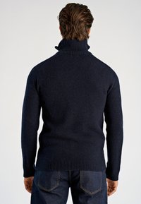 Marineblauer Strickpullover mit hohem Kragen, geripptem Saum und Bündchen sowie glatter Textur. Die Rückansicht zeigt keine markanten Muster.