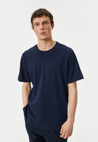 Marinblå bomullströja med rund hals och korta ärmar. Har en avslappnad passform och en mjuk, lätt textur.