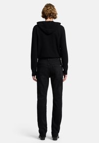 Felpa nera con cappuccio e coulisse regolabile, dal fit rilassato, abbinata a jeans neri a gamba dritta e stivali neri. Texture liscia con dettagli minimi.