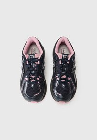 Chaussures de sport noires et roses avec une tige en maille, un système de laçage, un col rembourré et une semelle texturée avec détail de marque.