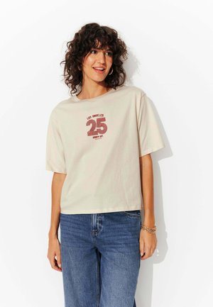 T-shirt en coton beige avec un col rond et des manches courtes. Présente un imprimé graphique en bordeaux avec le texte "LOS ANGELES 25 SPORTY DT."