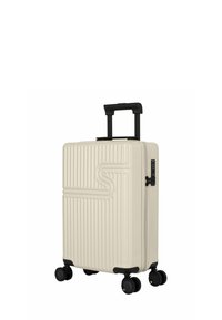 Harde koffer in crème met verticale ribbelstructuur, zwarte uittrekbare handgreep en vier draaibare wielen voor mobiliteit.