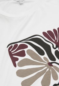 Vit t-shirt med stora blommönster i vinröd, svart och beige. Tillverkad av mjukt bomull, med rundad halsringning och slät yta.