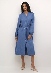 Blue long-sleeve dress with a buttoned front, tied waist, and gathered cuffs. Made from textured fabric with a mid-calf length.
