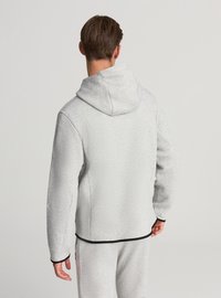 Felpa grigia con cappuccio e aspetto strutturato, con cappuccio e dettagli neri su polsini e orlo, vista da dietro.