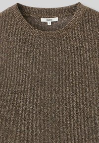 Pull en maille marron avec une texture côtelée, présentant des accents métalliques. Le col rond et l'étiquette indiquent la taille S.