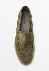 Mocassins en suède vert olive avec un bout arrondi, des coutures décoratives et une doublure intérieure lisse. Aucun matériel ou accent visible.
