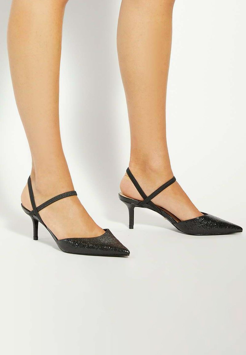 Black slingback heels with a pointed toe, textured upper, and two thin straps. Features a low stiletto heel for stability.