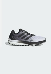 Zapatilla de trail running ligera en gris y negro, con parte superior de malla transpirable, puntera reforzada y amortiguación de media suela blanca. Logo de marca importante presente.