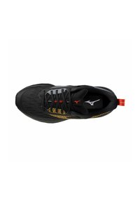 Chaussure de sport noire avec tige en mesh, accents argentés et motif doré. Équipée de lacets noirs et d'une languette rouge à l'arrière.