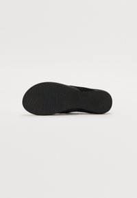 Black shoe sole with a wavy texture and subtle tread pattern, featuring a rounded shape and flat design. No visible brand markings.