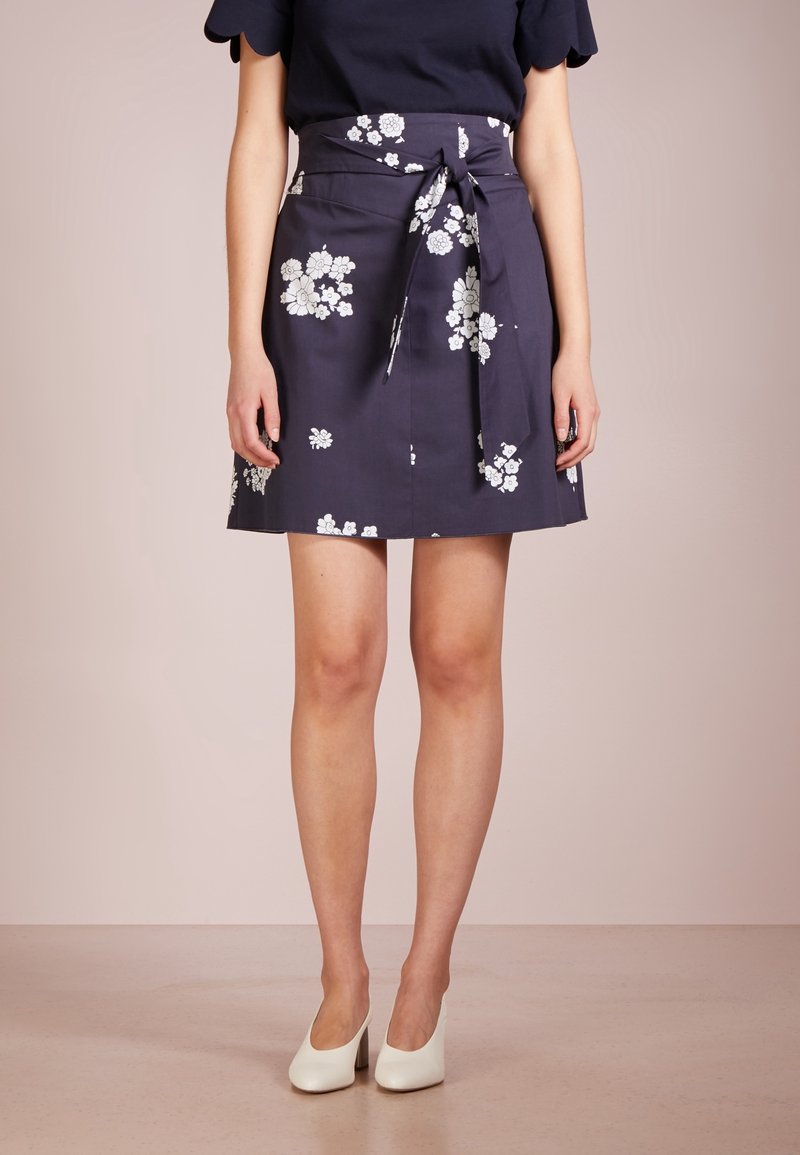 Laivari kukallinen hame, jossa on solmittava vyötärö ja valkoisia kukkapainatuksia. Kangas vaikuttaa sileältä ja kevyeltä, mikä tekee siitä sopivan lämpimille säille.