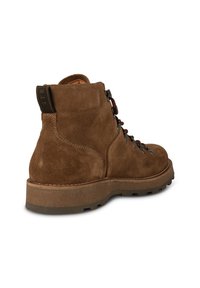Botte de randonnée en daim marron avec lacets bordeaux, œillets en métal, semelle épaisse à crampons, et languette de tirage noire avec l'inscription "STB" à l'arrière.