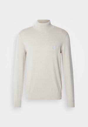 Jasno beżowy sweter z wysokim kołnierzem, wykonany z miękkiego dzianiny, z długimi rękawami i małą kwadratową naszywką z logo na piersi.