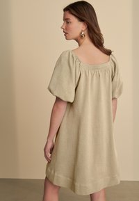 Hellgrünes, strukturiertes Kleid mit Puffärmeln und quadratischem Ausschnitt, mit gerafftem Rücken, endet oberhalb des Knies.