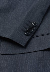 Navy blue suit fabric with horizontal pinstripes, featuring a cuff with four black buttons, and a subtle texture, emphasizing tailored design.