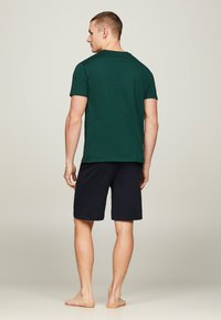 T-shirt verde in cotone con maniche corte, scollatura rotonda e pantaloni corti blu scuro. Abbigliamento casual progettato per il comfort, con una vestibilità semplice e classica.