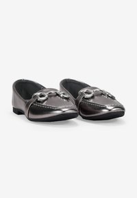 Mocasines metálicos grises con un acabado suave, suelas negras planas y un acento decorativo de cadena plateada en la parte delantera.