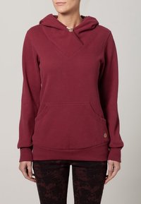 Burgundowa bluza z kapturem w dekolcie V, z regulowanym kapturem, kieszenią z przodu i logo na dolnym wykończeniu. Wykonana z miękkiego, teksturowanego materiału.