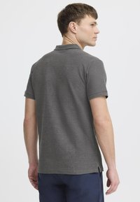 Charcoal gray polo shirt made of textured fabric, featuring a collar, short sleeves, and side slits at the hem for ease of movement.