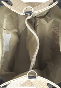 Beżowa pleciona torba typu tote wewnątrz z dwiema komorami; jedna kieszeń zapinana na zamek i gładka podszewka. Posiada srebrne okucia i skórzane akcenty.