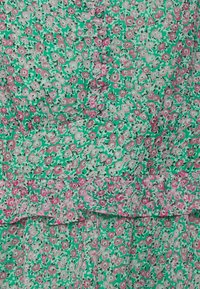 Vestido floral com fundo verde, flores rosa e brancas, bainha em camadas e tecido texturizado, criando um visual em camadas.