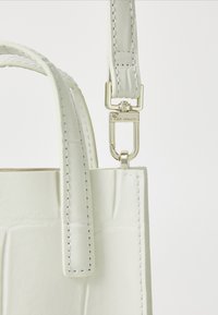 Weißes Lederhandtasche mit glatter Textur, die ein strukturiertes Design, auffällige Nähte und ein goldfarbiges Metallschließenakzent aufweist.
