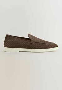 Mocassin pour homme en daim marron avec motif texturé et semelle en caoutchouc blanche, présenté de profil sur un fond neutre.
