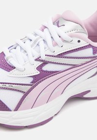 Scarpa da ginnastica viola e bianca realizzata in materiali in rete e sintetici, dotata di colletto imbottito, lacci bianchi e accenti testurizzati.