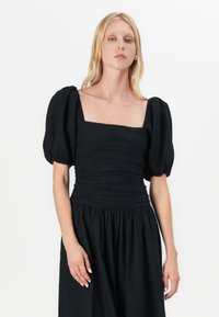 Abito nero con maniche a sbuffo corte, scollatura quadrata, corpetto strutturato e gonna piena. Realizzato in tessuto leggero con dettagli arricciati.