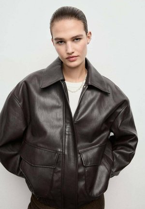 Chaqueta de cuero marrón con un collar amplio, dos bolsillos frontales y un ajuste relajado. Textura suave y detalle de costura visible.