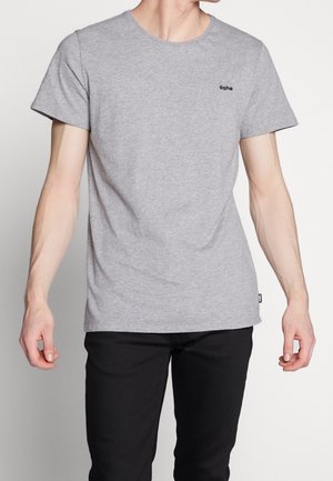 Szary bawełniany t-shirt z krótkimi rękawami, okrągłym dekoltem oraz małym czarnym logo na lewej piersi. Noszony z czarnymi spodniami o luźnym kroju.