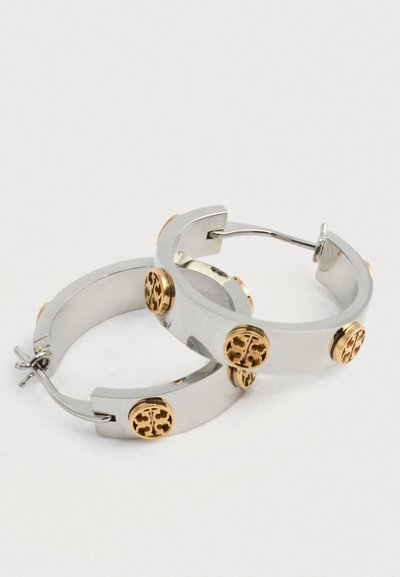 Ασημένιες σκουλαρίκια κρίκοι με στρογγυλές χρυσές λεπτομέρειες με περίπλοκα κομμένα σχέδια, λείο υλικό και μοντέρνα, μινιμαλιστική σχεδίαση.