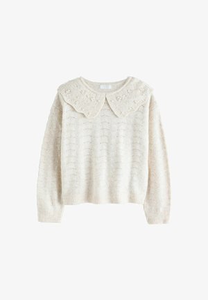 Kremasti pleteni pulover s valovitim ovratnikom koji ima male ukrase. Tijelo ima uzorak teksture, duge rukave i rebrasti rub.