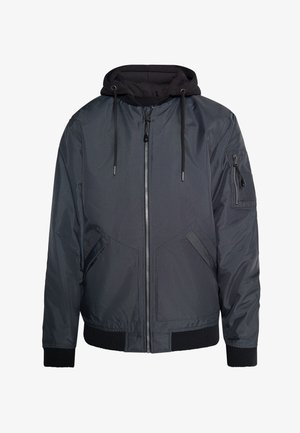 Hallide bomber-jakk, millel on lukuga esikülg ja külge õmmeldud must kapuuts. Omab soonikvarrukaid, külgtaskuid ja lukuga käistaskut. Sile tekstuur.