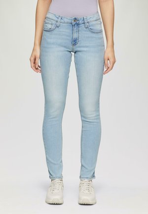 Světlé modré skinny džíny s vysokým pasem, které mají klasický design s pěti kapsami a jemné vyblednutí. V kombinaci se světlými teniskami.