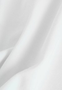 Tessuto bianco con una superficie liscia, caratterizzato da un delicato motivo a coste. Il materiale appare leggero e morbido, con pieghe e grinze sottili.